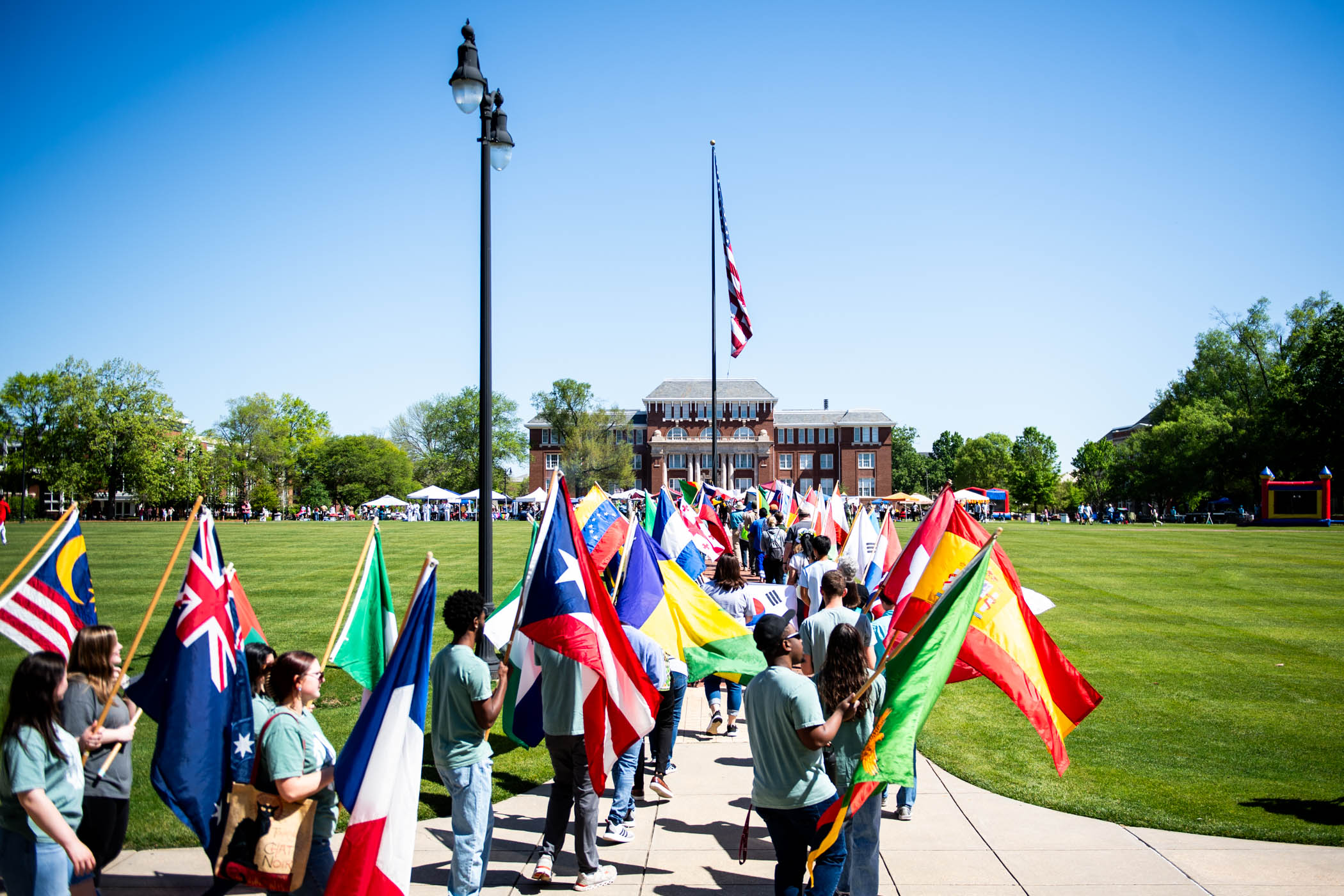 ֱ community members march vibrant flags of countries around the world through the center of the Drill Field to kick off the start of International Fiesta 2024.