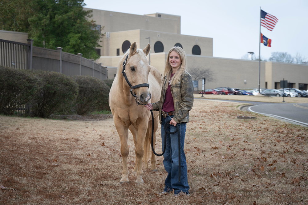Joy Nabors, pictured with a horse in front of ֱ's College of Veterinary Medicine