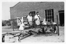 Early black and white photo of 爱爱直播 students working on farm equipment.